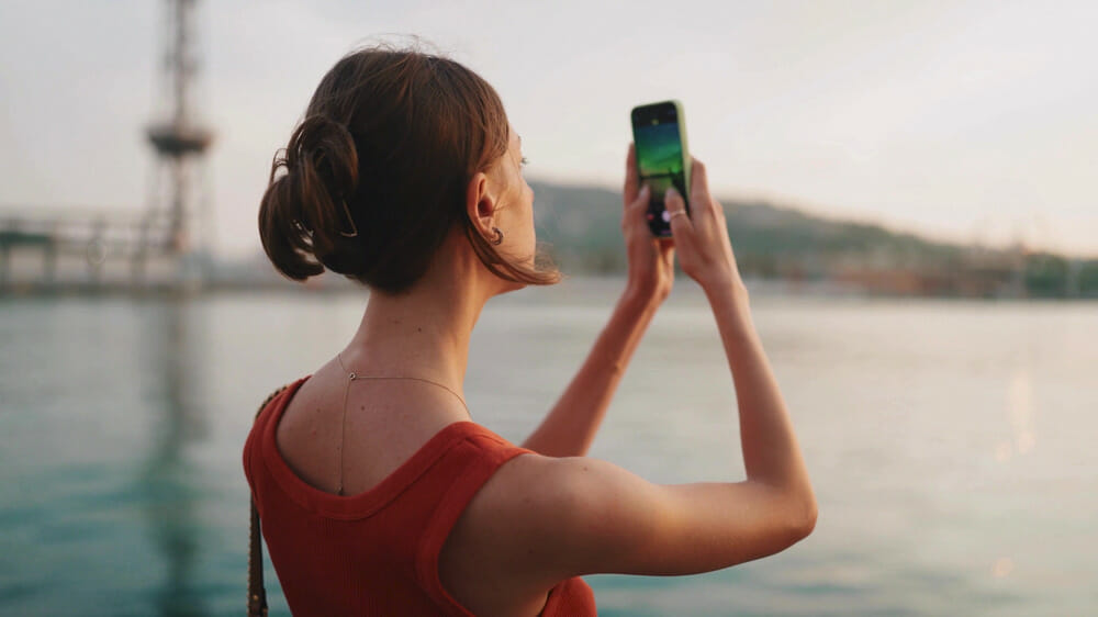 A woman filming on iPhone at a bay