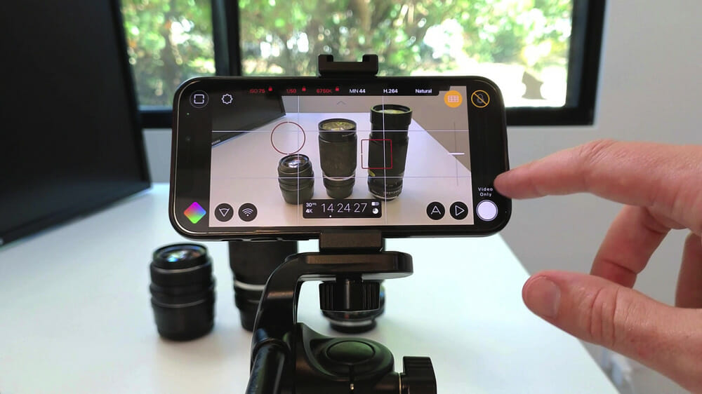 An iPhone in a stand while Justin Brown points to the FiLMiC Pro interface