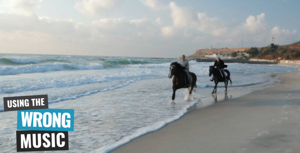 Two people riding horses on the beach