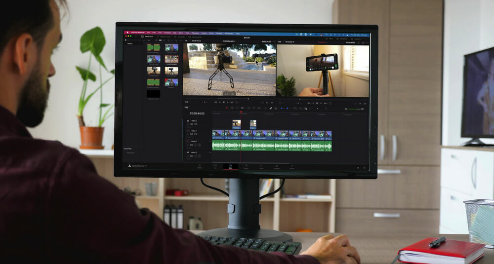A man sitting in front of a computer monitor editing with DaVinci Resolve